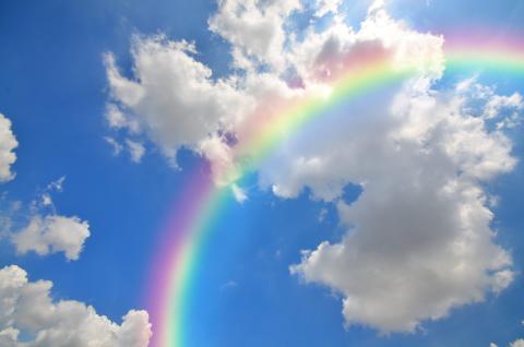 Rainbow in a blue sky with white clouds.