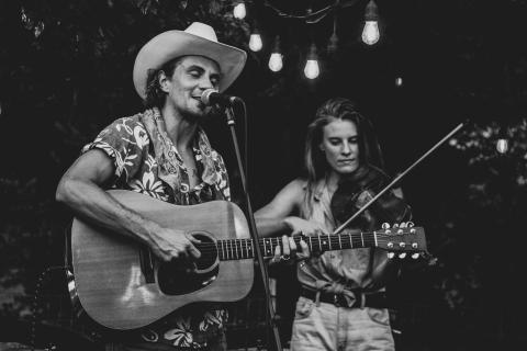 Forrest McCurren playing guitar with duo partner playing fiddle.