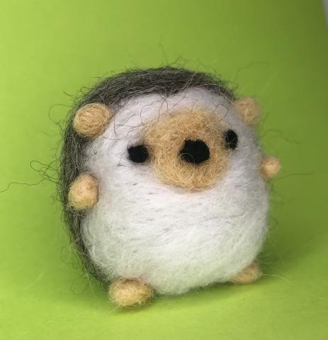 An image of a felt white and brown hedgehog.