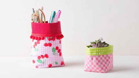 Two handmade fabric baskets holding office supplies.