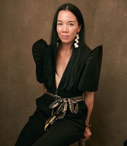 Author photo of Annabelle Tometich wearing a black outfit against a warm brown background.
