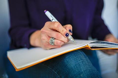 Woman writing in a notebook with a pen.