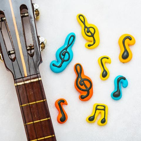 Neck of a guitar next to colorful music notes and symbols