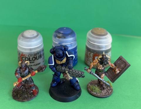 Photo of three painted miniatures with paint pots behind them. 