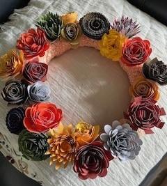 A handcrafted wreath of flowers in fall colors against a white background. 