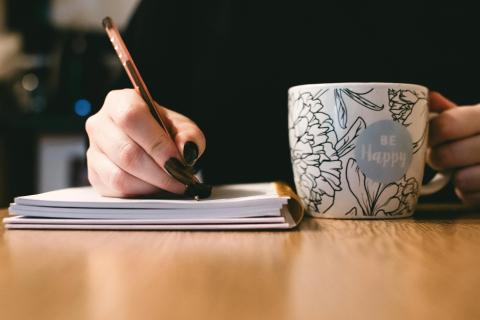 a woman writing with a mug