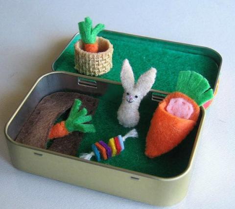 an altoid tin with a felt rabbit and carrots inside it. 
