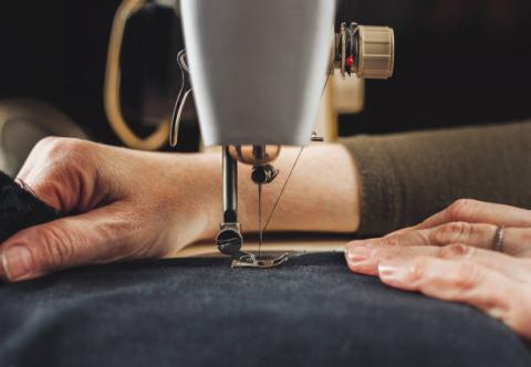 a close up of a person's hands using a sewing machine