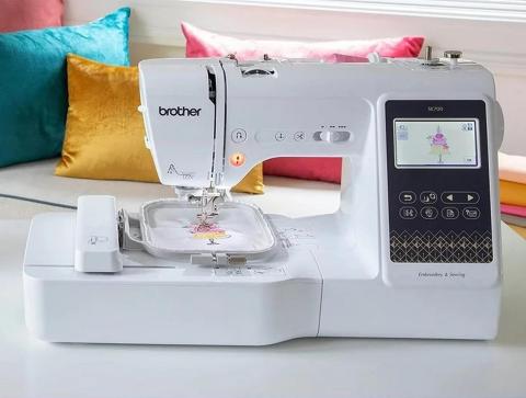 An embroidery machine against a backdrop of colorful pillows