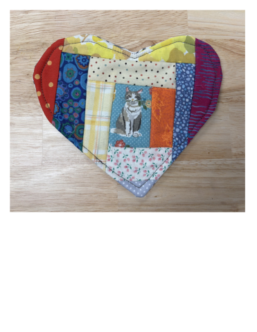 Multi-color quilted mug mat on wooden surface.