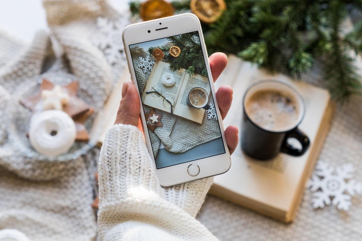 Tablet with camera view of open book and mug with hot chocolate