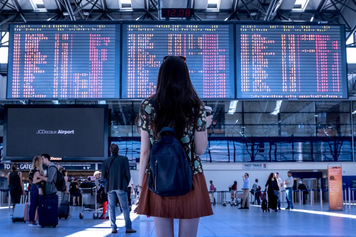 Girl in an airport looking at flight listings