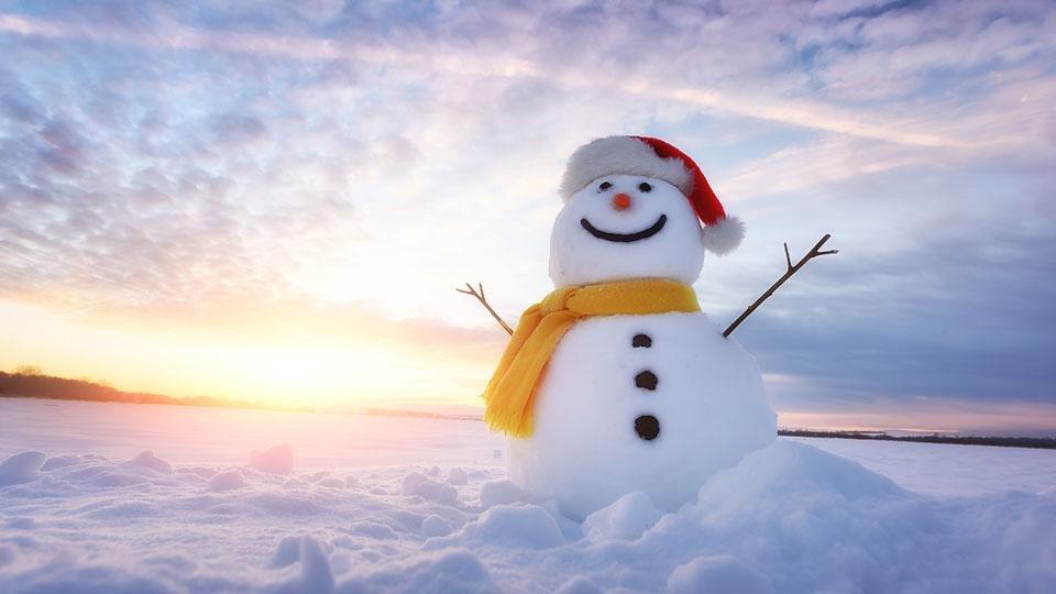 Snowman with yellow scarf and red hat with the sun behind him.