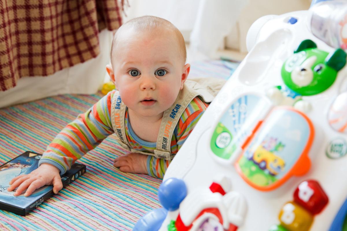 A baby on the floor playing with a toy.