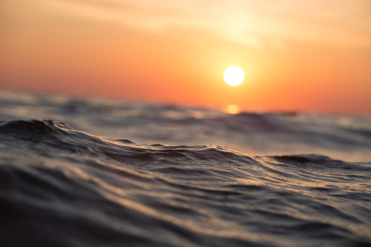 A picture of the sun setting over ocean waves.