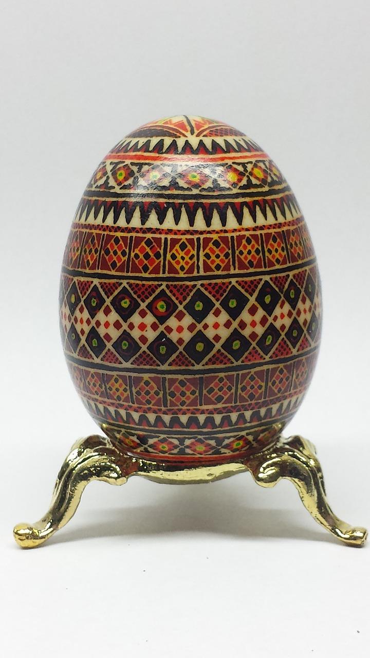 A picture of a Pysanka on a gold stand.