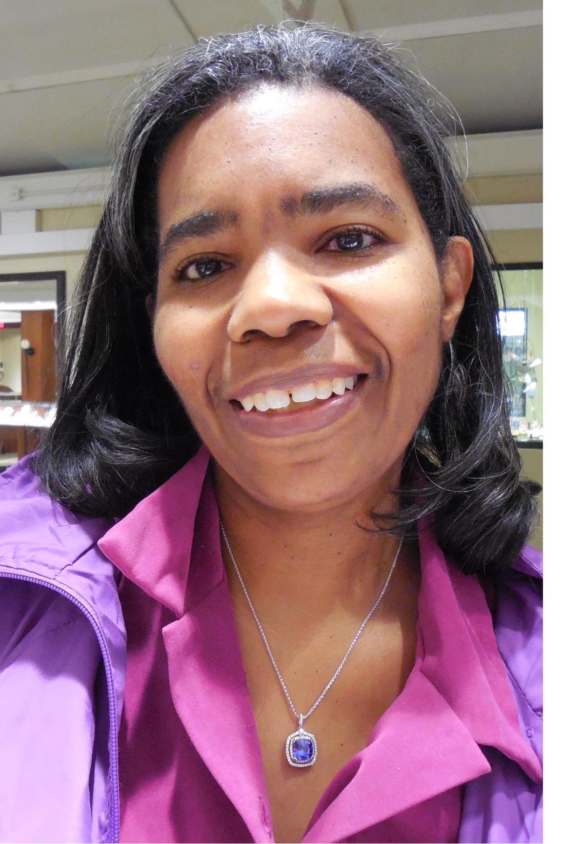 Cheryl Coleman wearing a pink blouse and purple jacket.