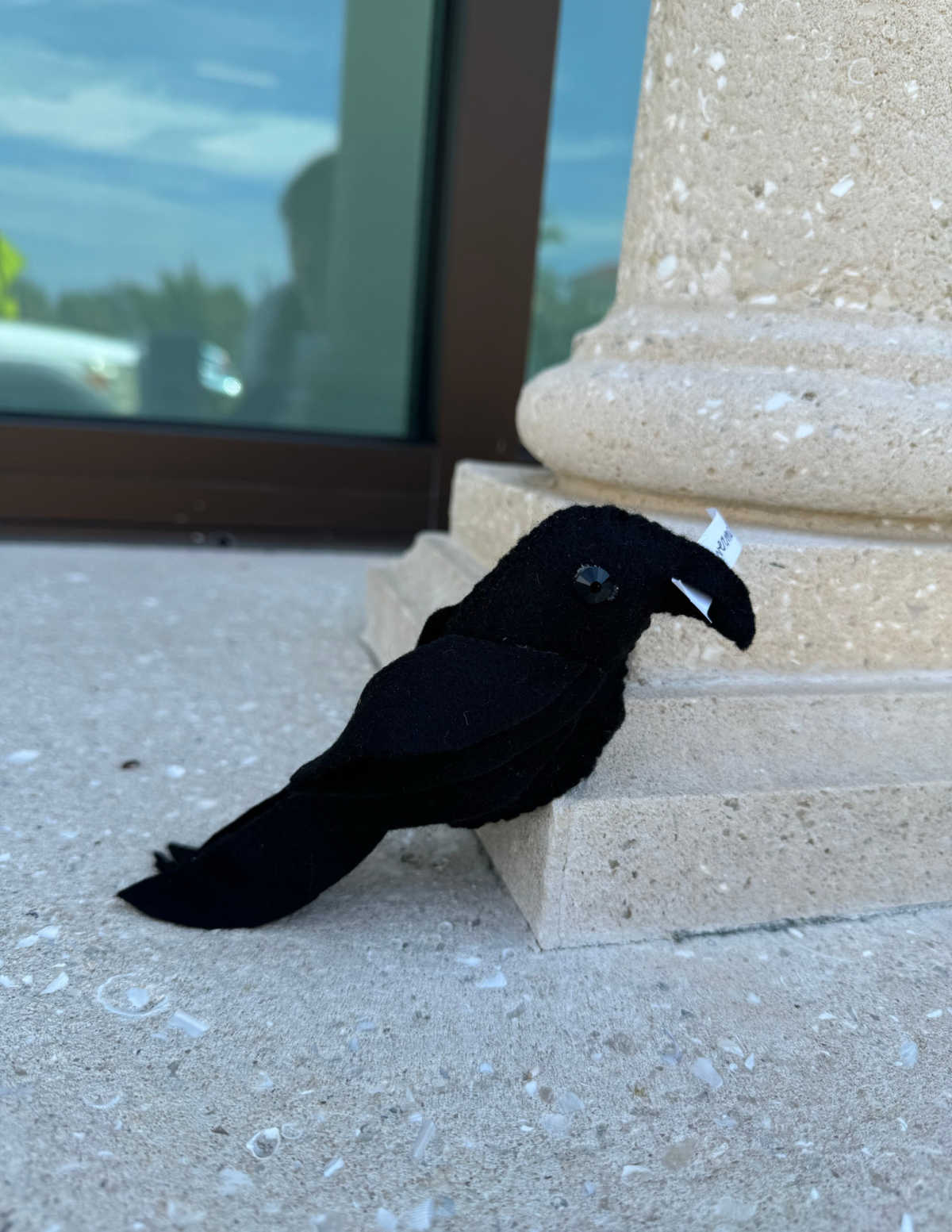 cute felt raven with a slip of paper in its mouth that says "nevermore"