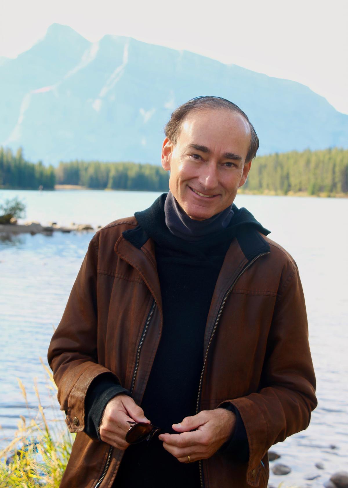 Author Chris Bohjalian outtdoors standing in front of a lake.