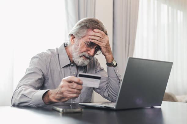 Older upset male with computer and credit card