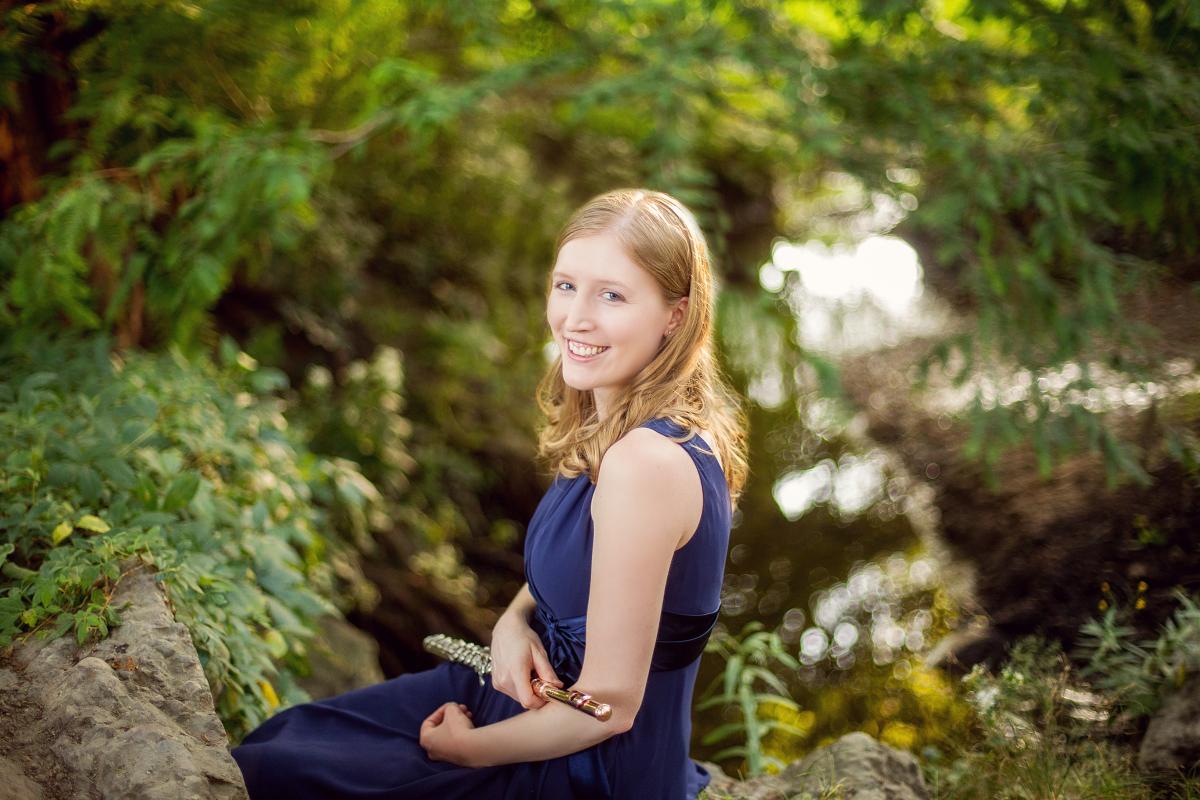 a woman sits in the woods with her flute