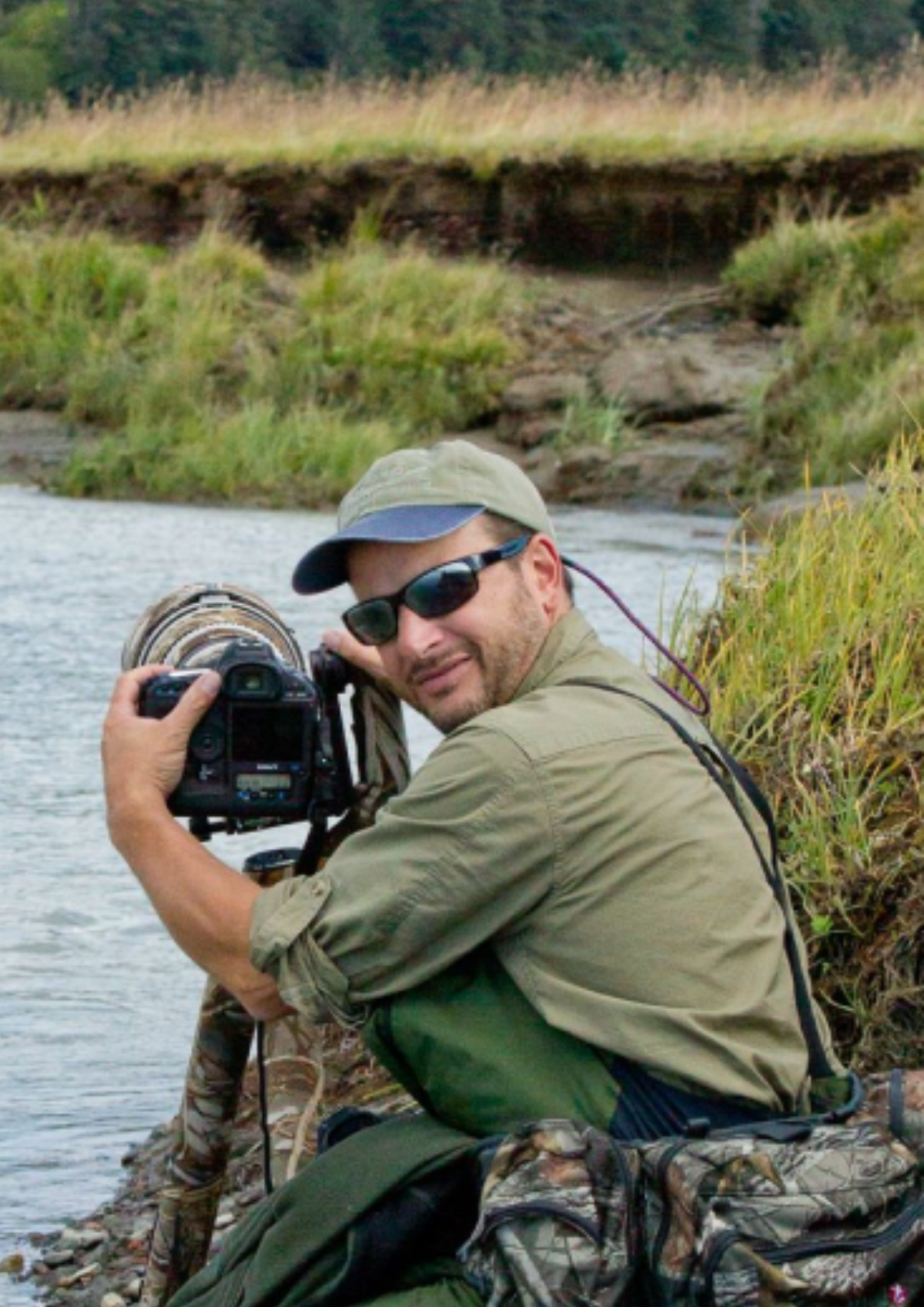 Author Stan Tejiela holding a camera outdoors near a river.