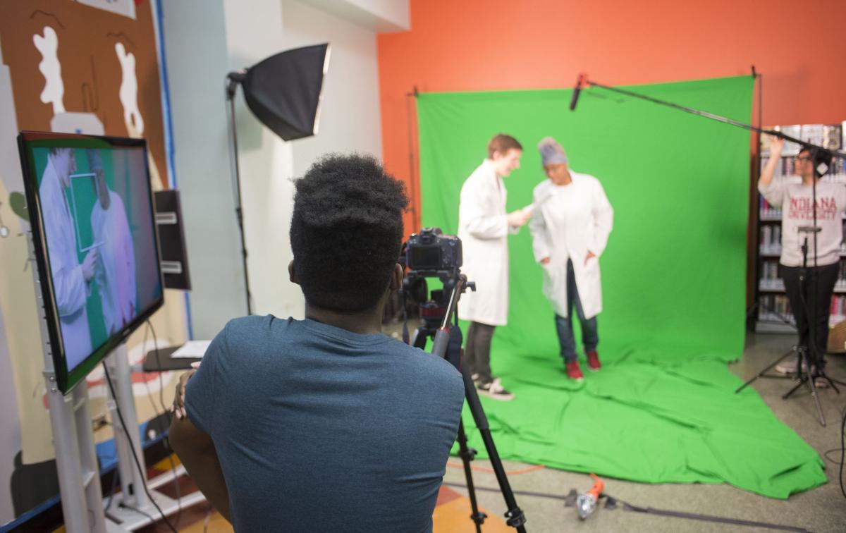 Actors in front of a green screen facing a video camera