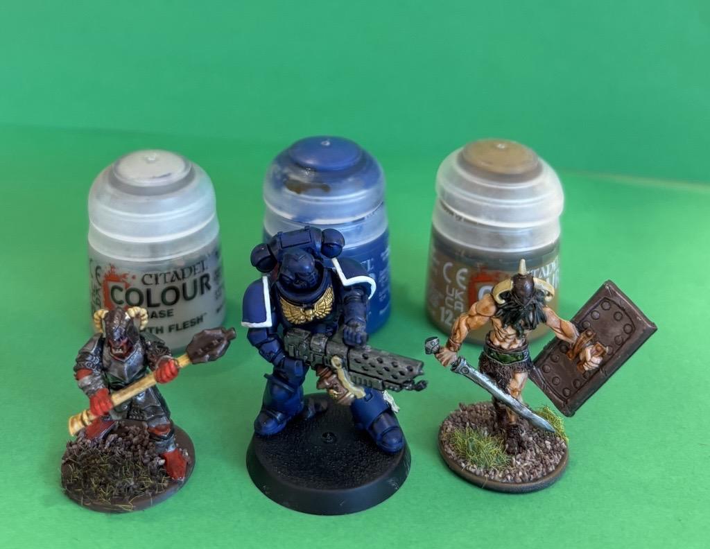 Photo of three painted miniatures with paint pots behind them. 