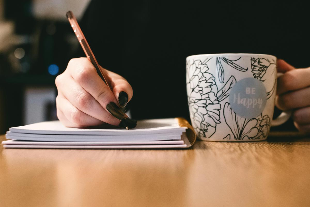a woman writing with a mug
