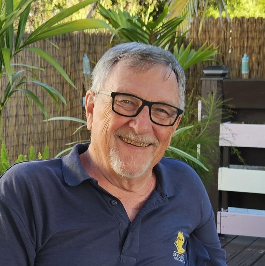 A photo of a smiling man in a dark blue polo and glasses.