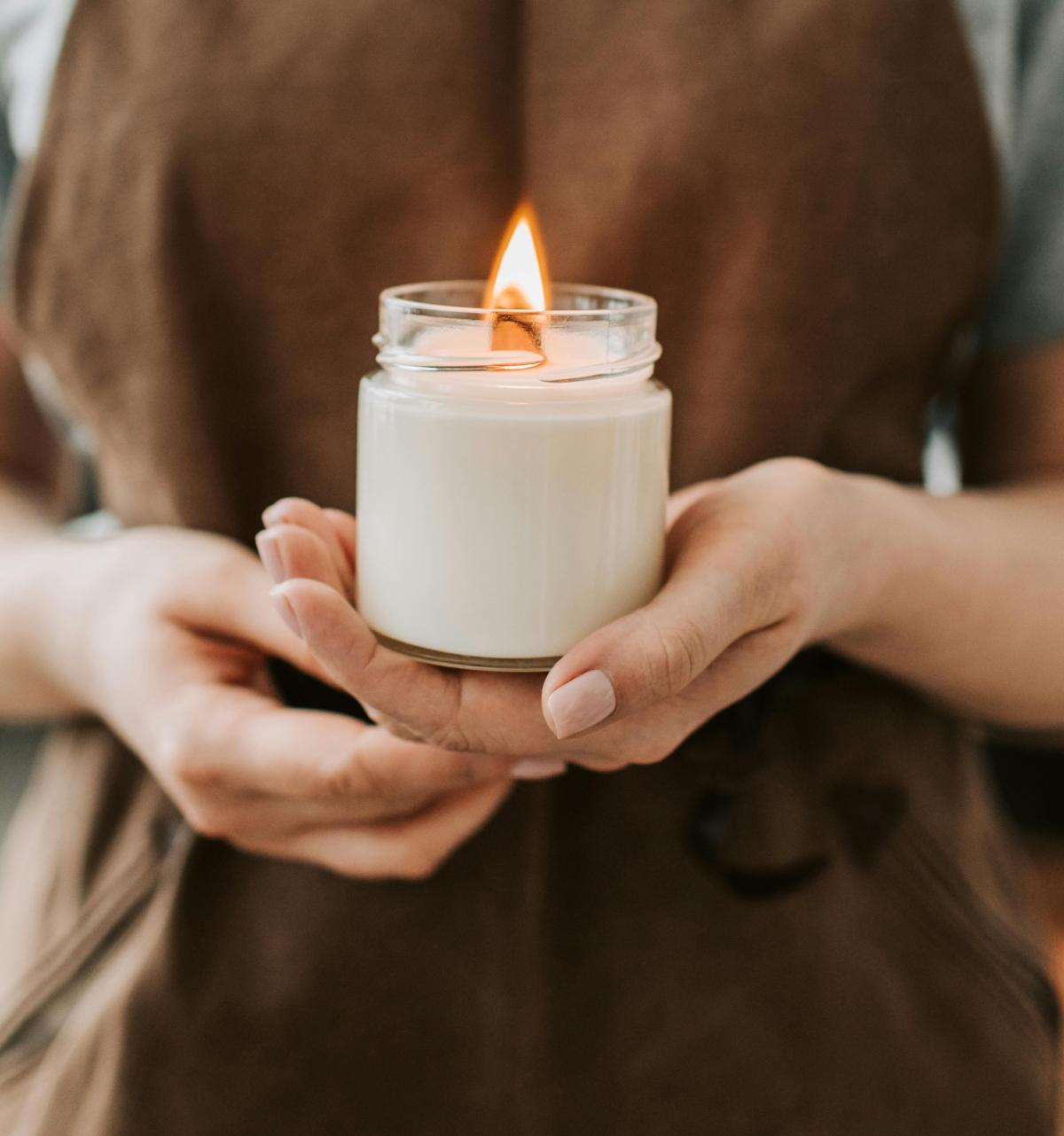 a person holding a lit, white candle