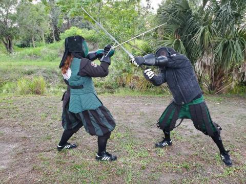 Two people in historical costumes sword fighting