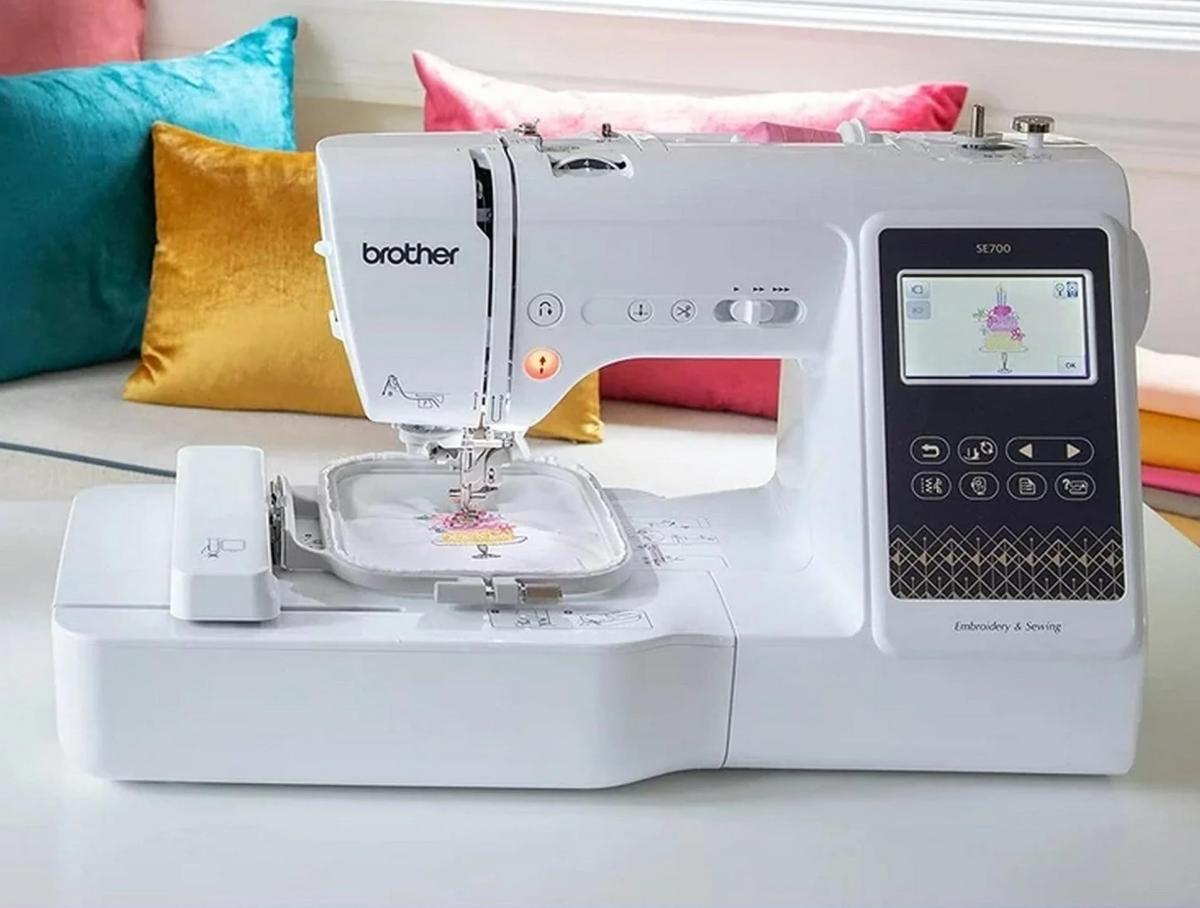 An embroidery machine against a backdrop of colorful pillows