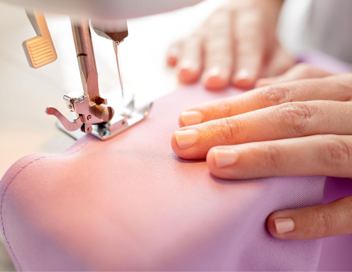 Close up of two hands using a sewing machine. 