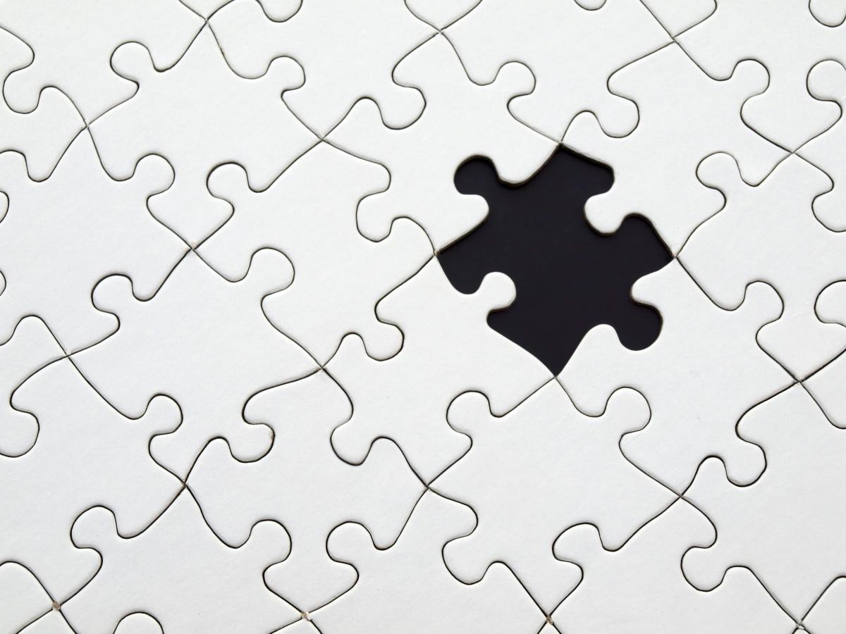 white puzzle pieces fitted together, with one missing piece